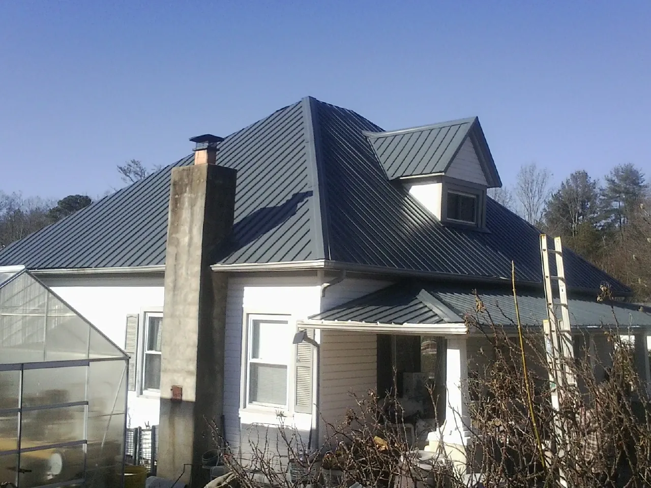 Dark blue standing seam metal roof on a white farmhouse with dormer — Slate & Tile Roof Repair by Roofing Brothers in Taylorville