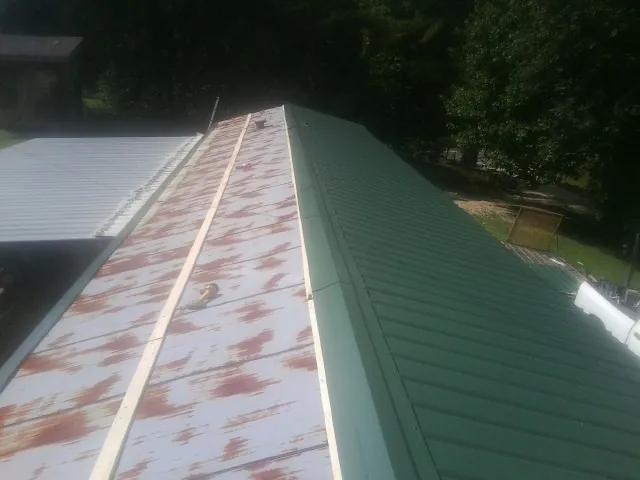 Old rusted panels beside newly installed green metal roofing — Wind Damage Roof Repair by Roofing Brothers in Taylorville