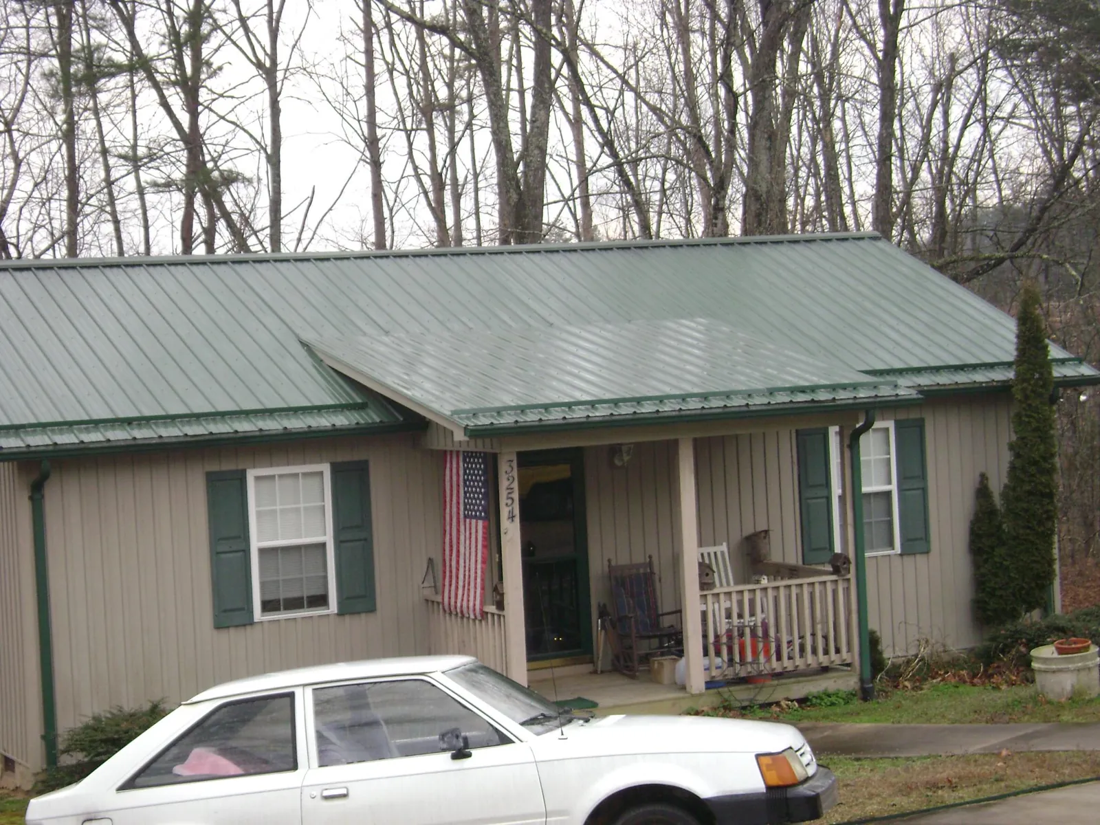 Green metal roof and front porch on a tan sided cottage in Taylorville