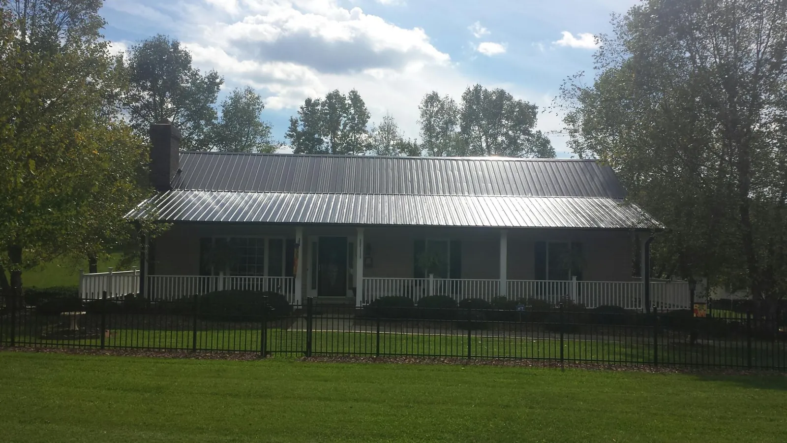 Gray metal roof on a brick ranch with a full width front porch — Gutter Guard Installation work by our crew in Taylorville