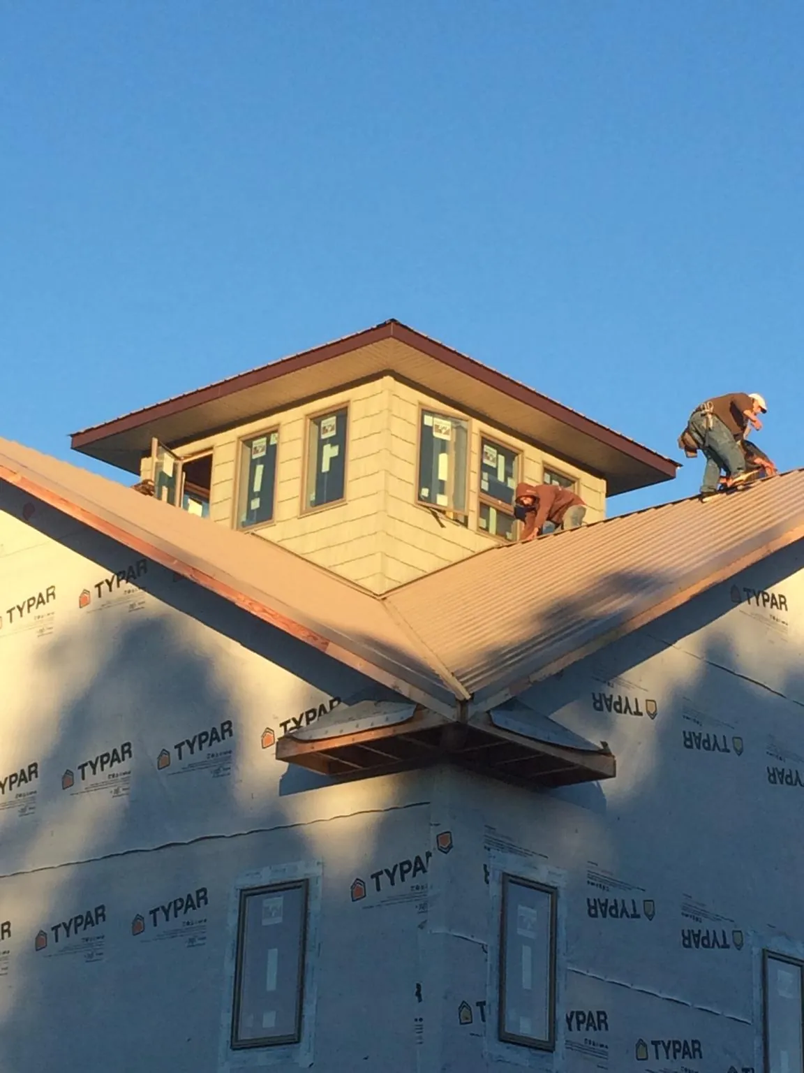 Roofers working around a rooftop cupola on a new metal roof at sunset — Roof Waterproofing in Taylorville by Roofing Brothers